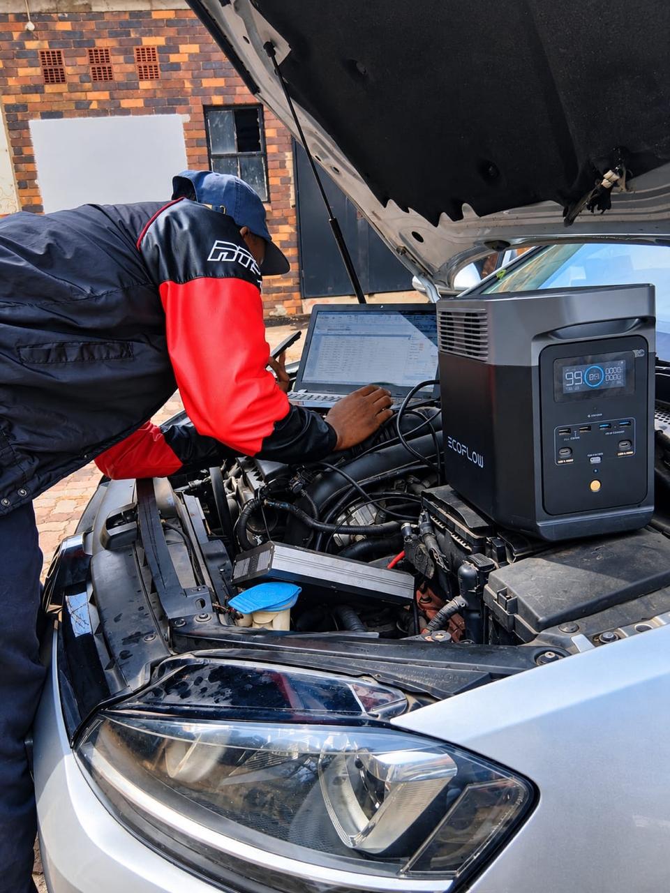 Technician connecting diagnostic equipment in an open engine bay