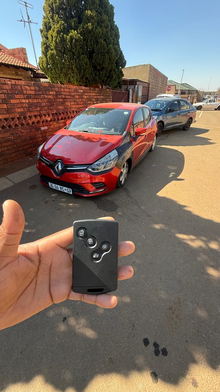 Programmed Renault card key held in front of a red Renault Clio